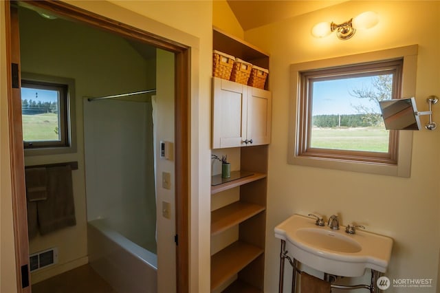 bathroom featuring visible vents, plenty of natural light, vaulted ceiling, and bathing tub / shower combination