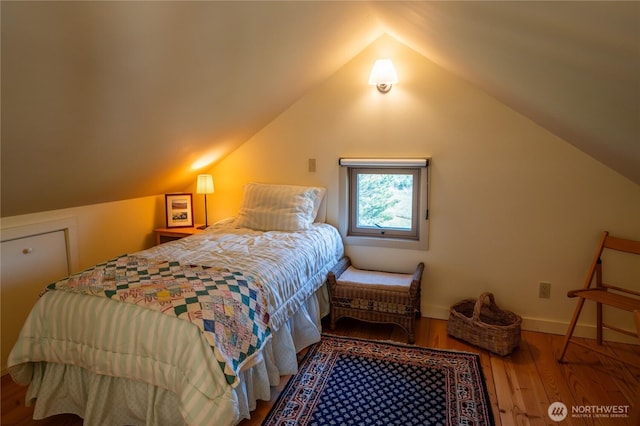 bedroom featuring baseboards, wood finished floors, and vaulted ceiling