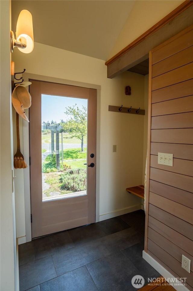 entryway featuring lofted ceiling, dark tile patterned flooring, and baseboards