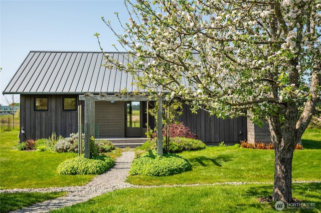 view of front of property with a standing seam roof, board and batten siding, a front yard, and metal roof