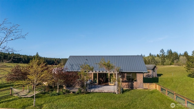 rear view of house with fence, a yard, and metal roof