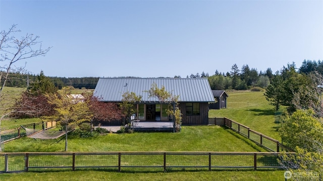 back of property with a porch, a rural view, a yard, fence private yard, and metal roof