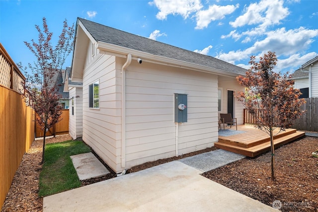 back of property with roof with shingles, a deck, a patio, and a fenced backyard