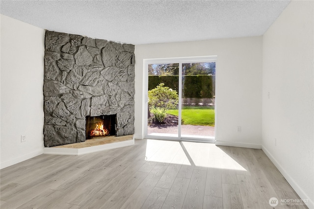 21615 80th Ave W Unit 101, Edmonds, WA 98026 - unfurnished living room with baseboards, a textured ceiling, wood finished floors, and a fireplace