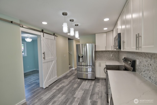 41 SE Wildcat Cove Rd, Shelton, WA 98584 - kitchen with stainless steel appliances, a barn door, wood finished floors, white cabinetry, and decorative backsplash