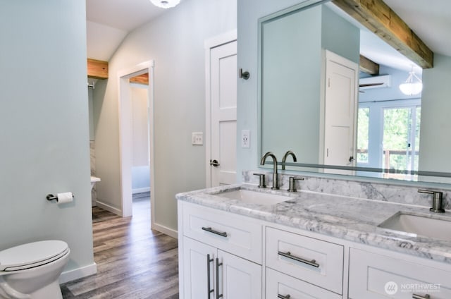 41 SE Wildcat Cove Rd, Shelton, WA 98584 - bathroom featuring wood finished floors, a wall unit AC, double vanity, baseboards, and lofted ceiling