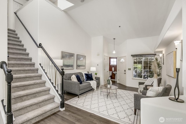 living area with baseboards, high vaulted ceiling, stairway, dark wood-type flooring, and a skylight