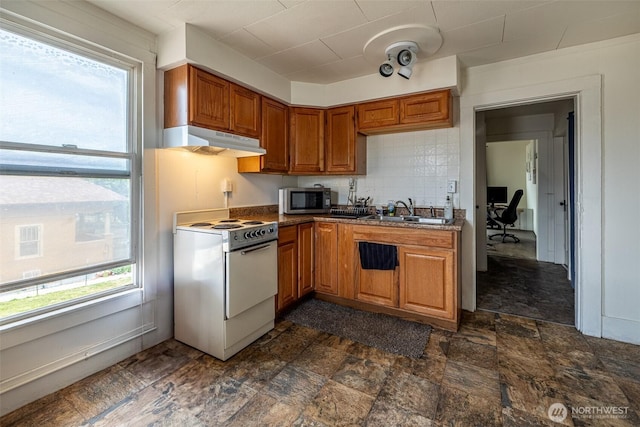 kitchen featuring electric stove, under cabinet range hood, stainless steel microwave, a sink, and brown cabinetry