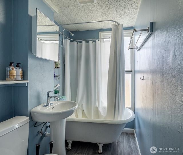 bathroom with wood finished floors, a paneled ceiling, toilet, baseboards, and shower / bath combo