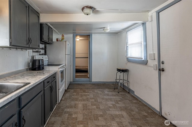 kitchen featuring white electric range oven, light countertops, a sink, brick patterned floors, and baseboards