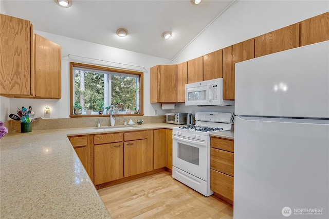 kitchen with white appliances, a sink, light countertops, vaulted ceiling, and recessed lighting