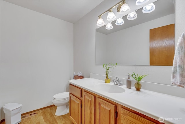 bathroom with wood finished floors, toilet, vanity, and baseboards