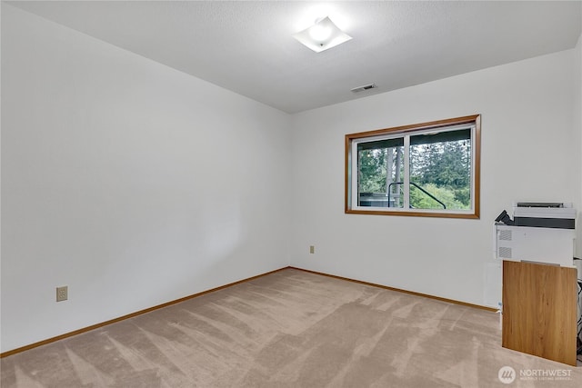 empty room featuring baseboards and light carpet