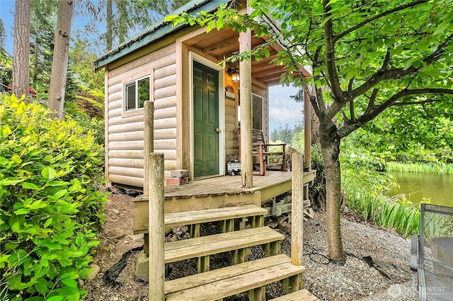 doorway to property featuring faux log siding, metal roof, and a water view