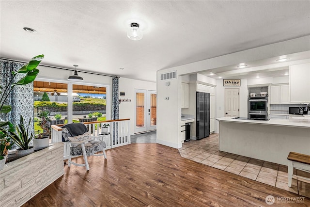 780 10th St NE, East Wenatchee, WA 98802 - kitchen with freestanding refrigerator, double oven, white cabinets, light wood-style flooring, and light countertops