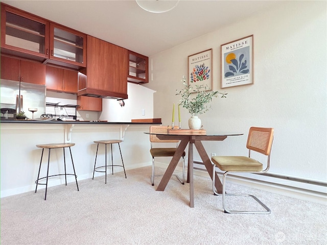 7309 Sand Point Way NE Unit B727, Seattle, WA 98115 - kitchen with glass insert cabinets, a breakfast bar area, light carpet, dark countertops, and stainless steel fridge with ice dispenser