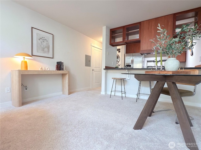 7309 Sand Point Way NE Unit B727, Seattle, WA 98115 - kitchen featuring stacked washer / dryer, stainless steel fridge, light colored carpet, and glass insert cabinets