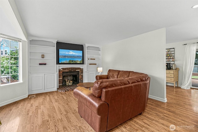 living area with baseboards, light wood-style flooring, and a fireplace