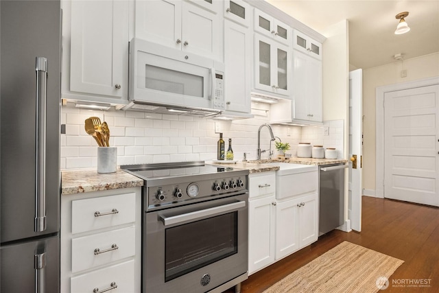 kitchen featuring dark wood-style floors, white cabinets, tasteful backsplash, a sink, and premium appliances