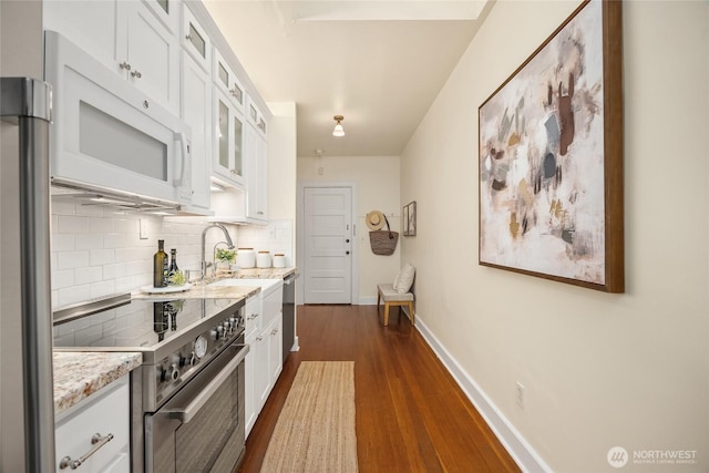 kitchen featuring appliances with stainless steel finishes, decorative backsplash, baseboards, and white cabinets