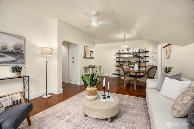living area with baseboards, arched walkways, ceiling fan, and wood finished floors
