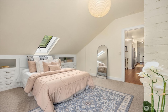 bedroom featuring freestanding refrigerator, lofted ceiling with skylight, and carpet flooring
