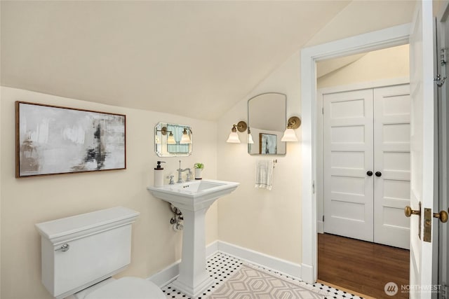 bathroom featuring baseboards, vaulted ceiling, and toilet