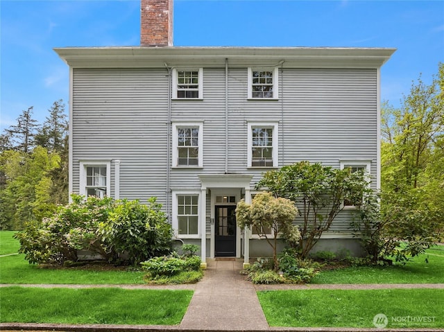 view of front of house with a front yard and a chimney