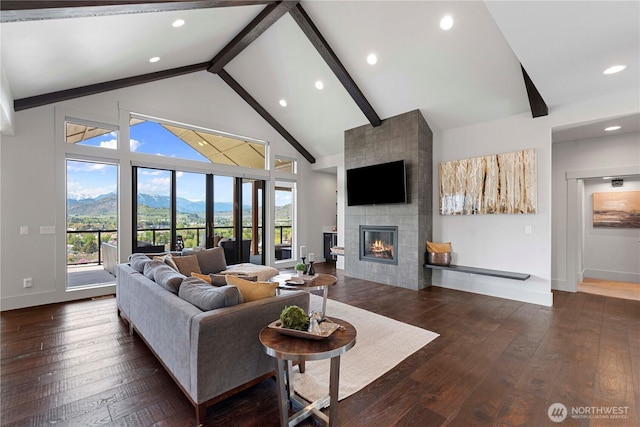 living room featuring beamed ceiling, a tiled fireplace, hardwood / wood-style flooring, and baseboards