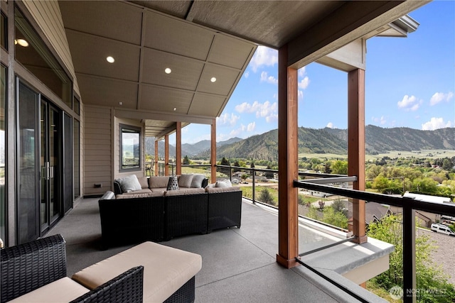 view of patio with an outdoor living space, a mountain view, and a balcony