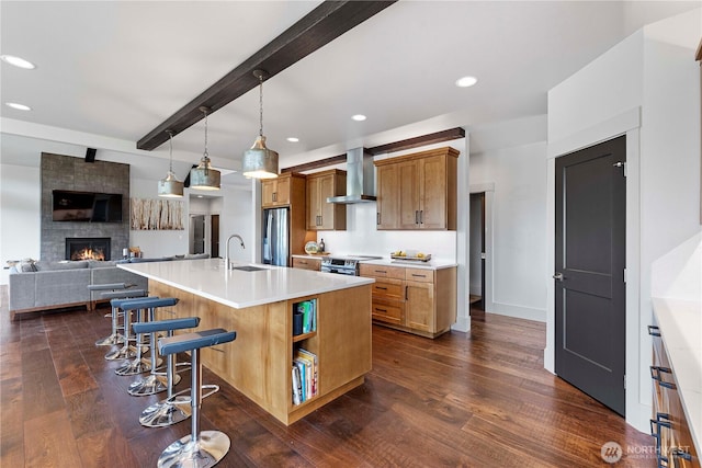 kitchen with a sink, open floor plan, dark wood finished floors, and wall chimney exhaust hood