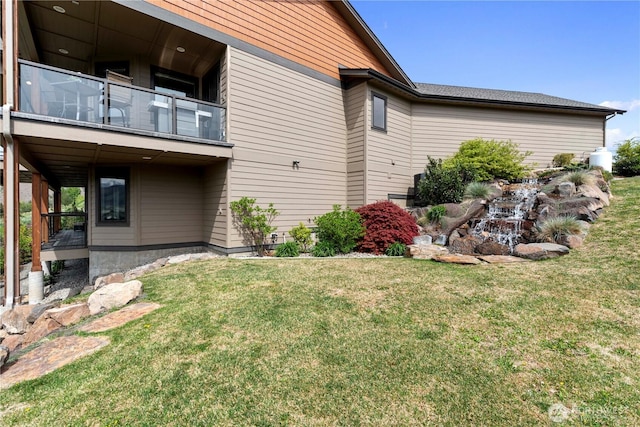 view of home's exterior with a balcony and a lawn