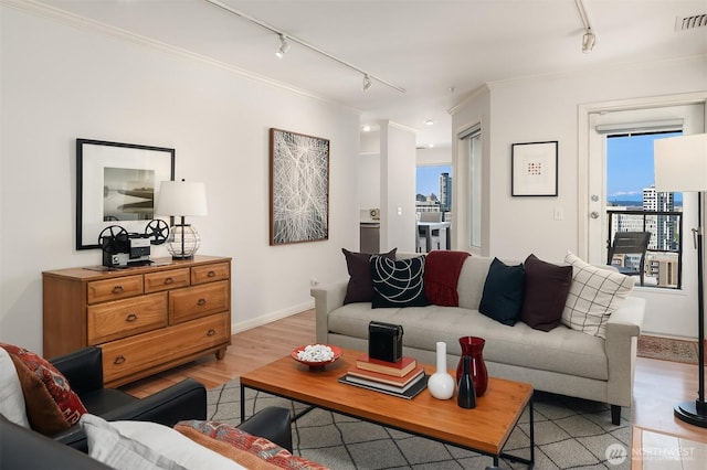 living room with crown molding, light wood-type flooring, rail lighting, and visible vents