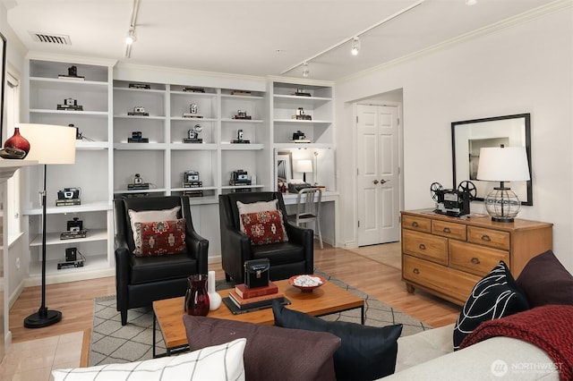 living room with track lighting, ornamental molding, light wood-style floors, and visible vents