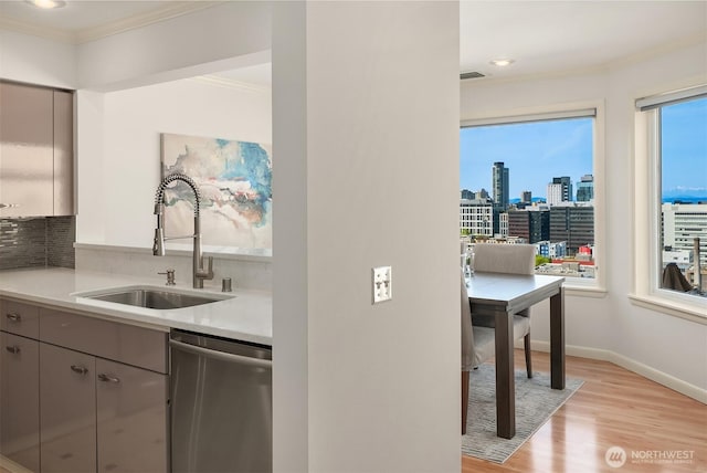 kitchen with crown molding, light wood-type flooring, a sink, dishwasher, and gray cabinetry