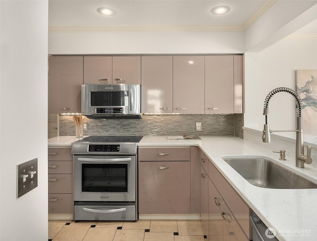kitchen featuring light tile patterned flooring, appliances with stainless steel finishes, a sink, decorative backsplash, and ornamental molding