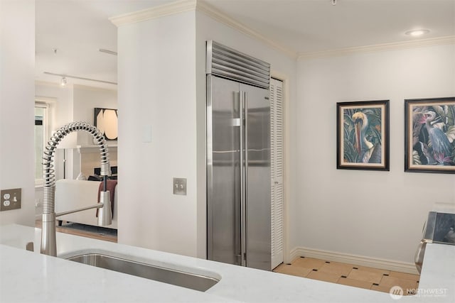 interior space with stainless steel built in fridge, a sink, baseboards, a closet, and ornamental molding