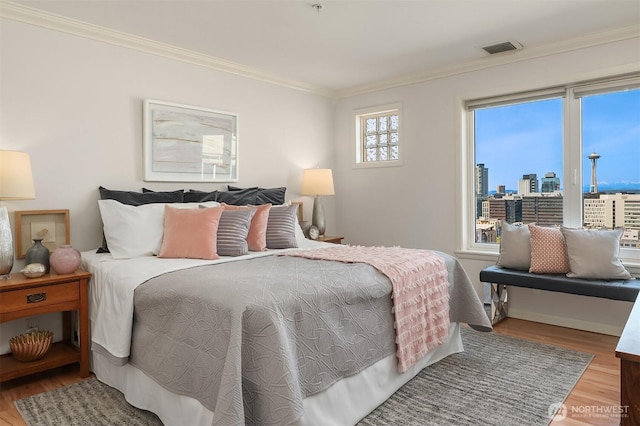 bedroom with crown molding, a city view, visible vents, and wood finished floors