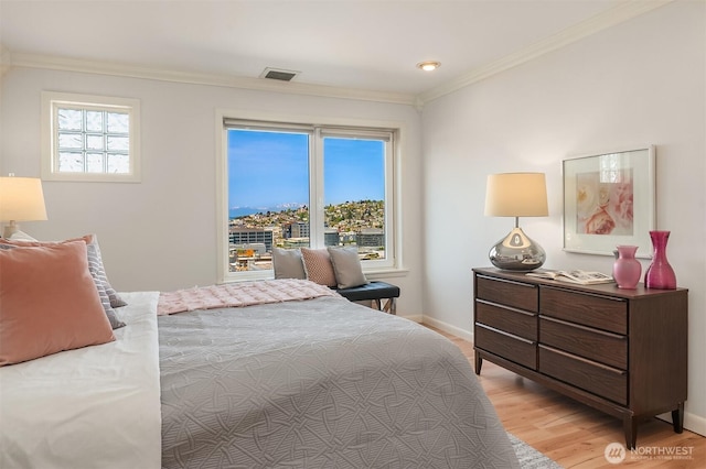 bedroom with crown molding, baseboards, visible vents, and light wood finished floors