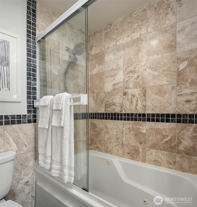 full bath featuring toilet, shower / bath combination with glass door, and tile walls