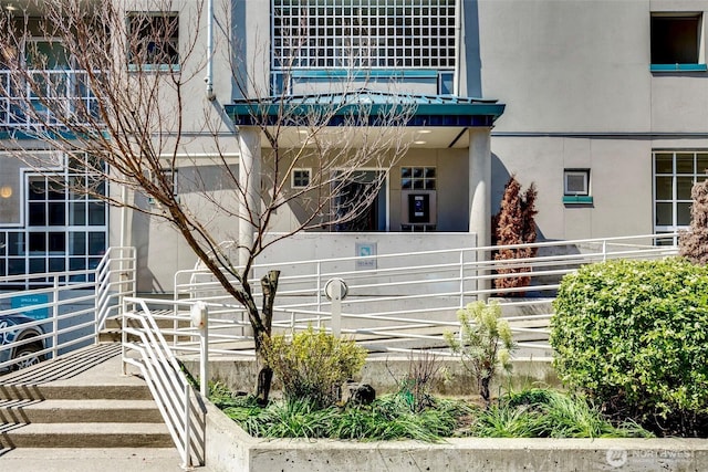 view of exterior entry with stucco siding, fence, and a balcony