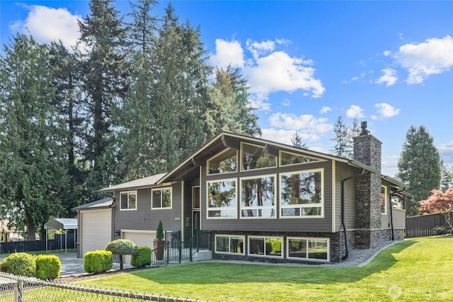 back of house featuring a lawn, fence, a chimney, and a garage
