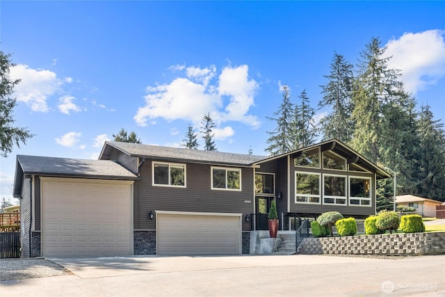 split foyer home featuring an attached garage, stone siding, and concrete driveway