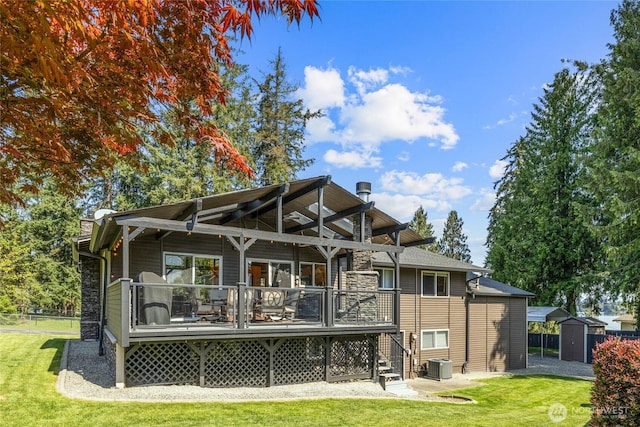 back of property with a storage shed, a deck, an outbuilding, central AC unit, and a yard