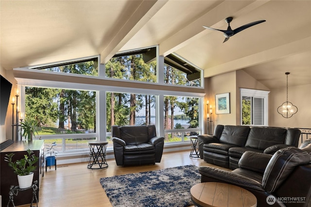 living area with a water view, lofted ceiling with beams, a healthy amount of sunlight, and wood finished floors