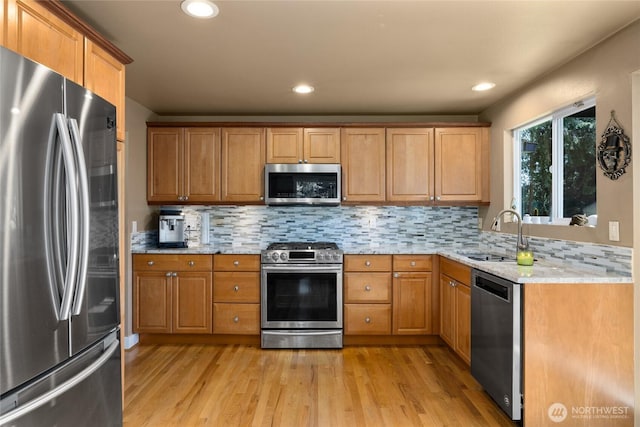 kitchen featuring a sink, tasteful backsplash, light wood-style floors, and stainless steel appliances