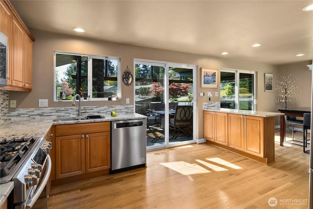 kitchen with appliances with stainless steel finishes, plenty of natural light, a sink, and light wood-style flooring
