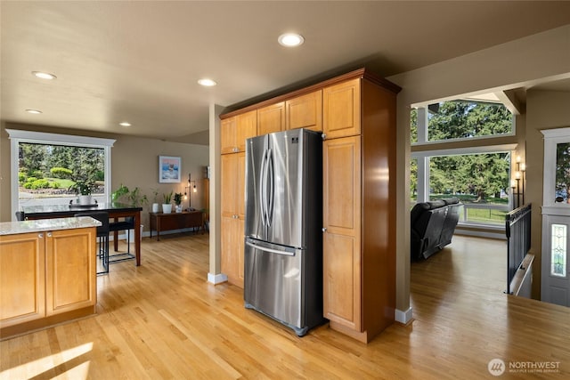 kitchen with recessed lighting, freestanding refrigerator, light wood-style flooring, and light stone countertops