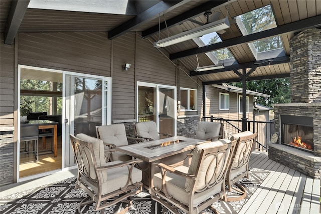wooden terrace featuring an outdoor stone fireplace and a fire pit