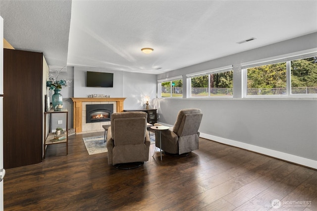 living area with visible vents, hardwood / wood-style floors, a fireplace, baseboards, and a textured ceiling
